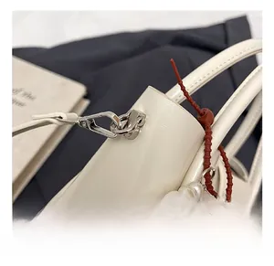 Close-up of premium silver metal hook with pearl strap and cartoon charm on leather bag