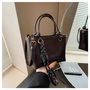 Détail d'un sac à bandoulière marron café en similicuir avec un charm en corde tressée