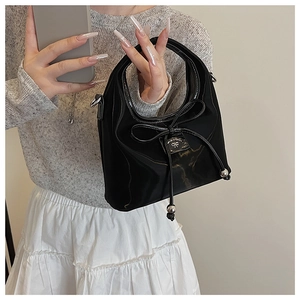 Détail du sac à main en satin noir avec nœud en soie et plaque logo en argent poli