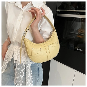 Close-up of a yellow pebbled leather crescent hobo bag with stud detailing on the front