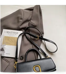 Détail du sac à main noir montrant la bandoulière réglable et la boucle dorée en forme de U