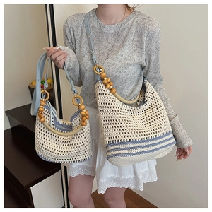 Détail du sac seau au crochet beige avec bandoulière en cuir bleu et perles en bois