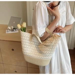 Dettaglio della borsa tote in pizzo intrecciato con motivi floreali e tracolla in tessuto