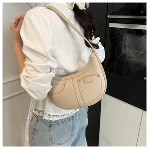 Beige lychee-grain hobo bag with double pockets and silver rivets on model shoulder