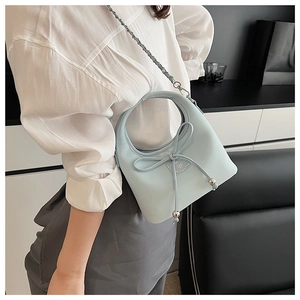 Détail du sac bleu clair avec nœud décoratif et bandoulière en chaîne métallique