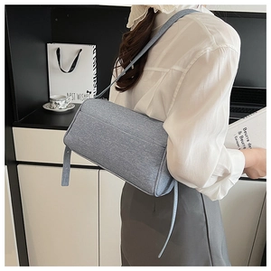Chic light blue textured fabric baguette bag shown in a minimalist lifestyle setting