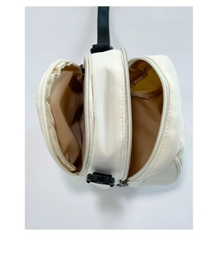 Detail of minimalist beige shell bag with triple zipper layers and internal storage compartments
