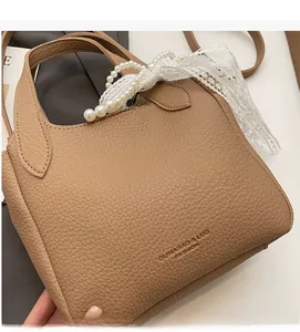 Detail shot of brown lychee grain leather handbag with dual handles and logo print