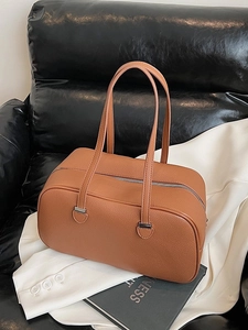 Brown litchi grain leather shoulder bag with long straps on a sofa and suit