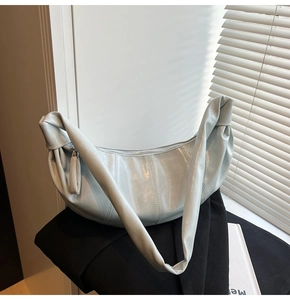 Detail of light blue pleated croissant bag showing high-gloss leather texture and seams