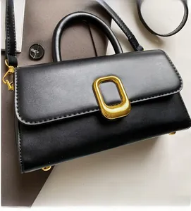 Détail d'un sac carré en cuir noir mat avec une boucle métallique rectangulaire dorée