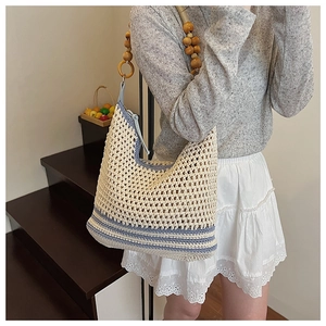 Détail du sac seau en tricot à rayures bleues et bandoulière décorative en perles de bois