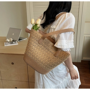 Dettaglio di borsa tote in paglia intrecciata a mano con motivi traforati e interno ampio