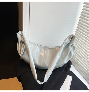 Detail of light blue crescent bag with glossy finish and stylish pleat details