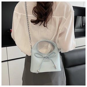 Détail du sac à bandoulière bleu clair avec nœud décoratif et poignée ronde