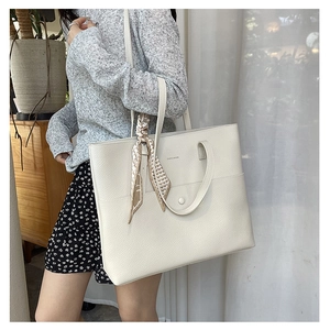 Detail of cream white tote bag in lychee leather featuring a stylish handle scarf