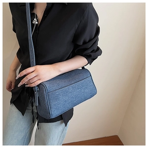 Chic blue denim cylinder shoulder bag styled with a black shirt and jeans