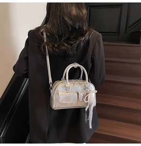 Silver metallic Boston bag with crinkle texture and lace pearl charm on dark stairs