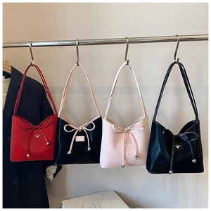 Détail de quatre sacs à main colorés avec nœuds en ruban et breloques sur crochets