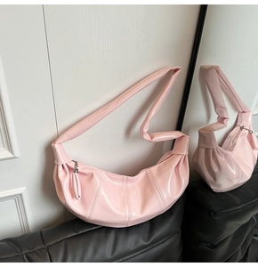 Detail of light pink patent leather dumpling bag with pleated texture and knot strap