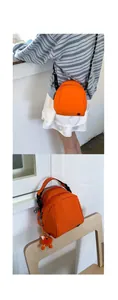 Detailed view of an orange mini shell crossbody bag with woven strap and plush charm