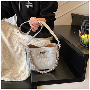 Dettaglio della borsa a secchiello in pelle grigia con catena argento e chiusura