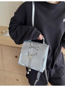 Sac bandoulière argenté avec breloques papillon et rubans porté par un mannequin femme