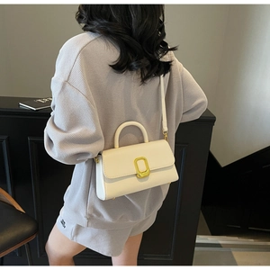 Mannequin portant un sac à main carré crème minimaliste avec fermoir doré et poignée