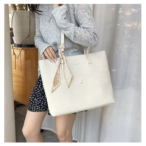 Close-up of a white lychee grain leather tote bag with decorative floral silk scarf details
