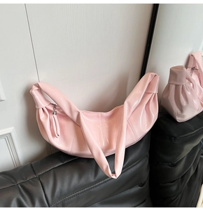 Detail of light pink crescent croissant bag with pleated stitching and smooth texture
