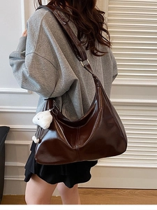 Large dark brown leather hobo bag with plush cloud charm shown on shoulder