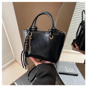 Détail du sac seau noir verni avec poignée ronde et cordon tressé avec pendentif raquette