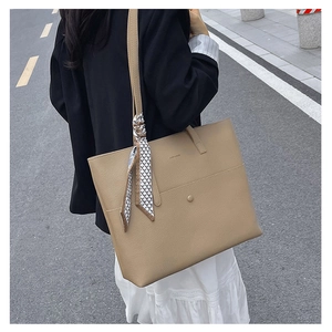 Street view of khaki leather tote bag with geometric silk scarf detail on shoulder