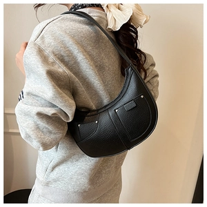 Detail of black pebbled leather crescent bag with silver studs and visible texture