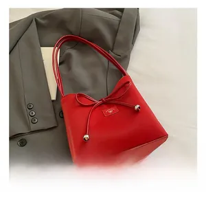 Détail macro du sac à bandoulière en cuir rouge avec nœud décoratif et perles argentées