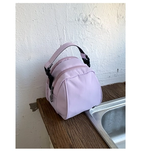 Detail view of the lilac shell bag with top handle, dual zippers and round silhouette