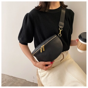 Close-up of black lychee grain leather crossbody bag with golden hardware and nylon strap