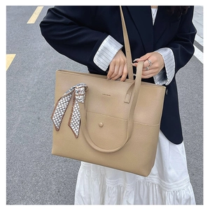 Close-up of beige lychee leather tote bag featuring a decorative patterned silk scarf