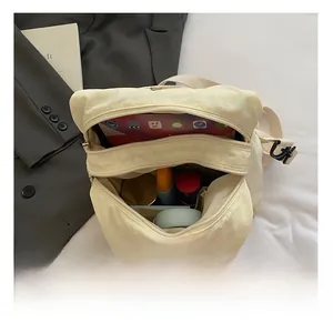 Detailed view of beige nylon crossbody bag showing spacious interior with multi-layer storage