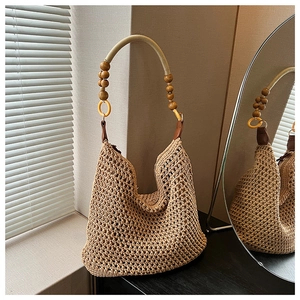 Détail du sac seau en maille beige ajourée avec anse en perles de bois et cuir