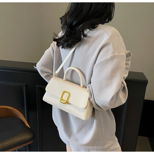 Vue arrière du mannequin portant un sac carré blanc minimaliste avec fermoir doré