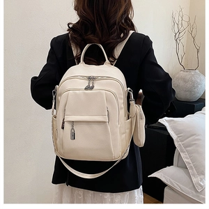 Detail of cream leather backpack with multi-pockets and a small round coin purse charm