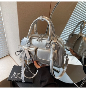Detail of silver metallic Boston bag featuring pearly lace bow and vintage texture