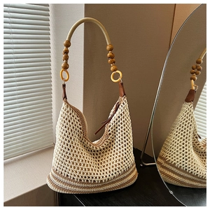 Détail du sac seau en tricot avec perles en bois, anneaux ambrés et base rayée