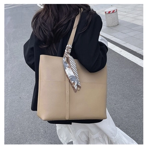 Close-up of khaki pebbled leather tote bag featuring a decorative printed silk scarf
