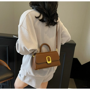 Détail d'un sac rectangulaire en cuir marron avec boucle en métal doré et bandoulière