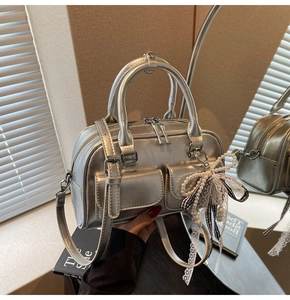 Close-up of silver Boston bag featuring twin pockets and decorative pearl bow charm