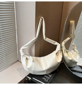 Detail view of the cream off-white pleated crescent bag with a glossy textured finish