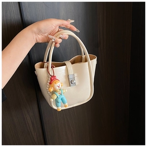 Cream bucket bag featuring a silver metal clasp and a cute cartoon girl pendant