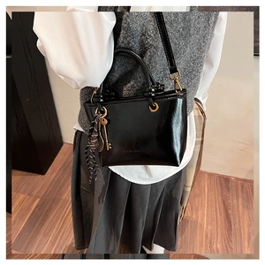 Détail du logo embossé sur le sac en cuir verni noir avec un porte-clés à rayures